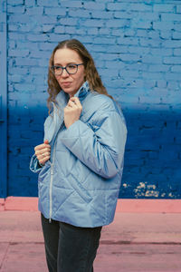 Portrait of young woman standing against wall