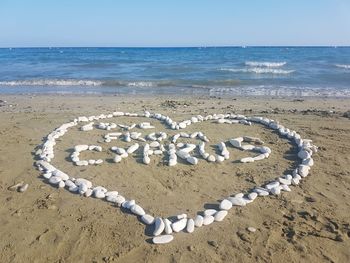 Text on sand at beach against sky