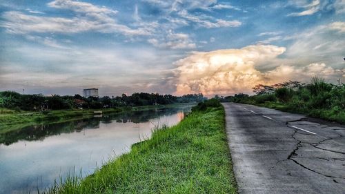 Road by grass against sky