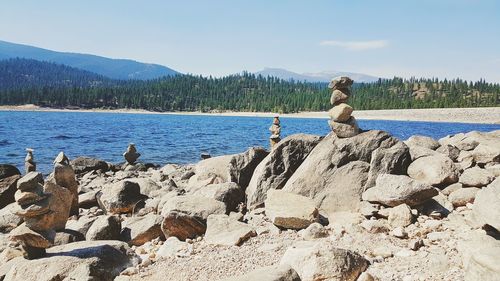 Woman sitting on rock by sea against sky