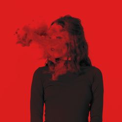 Young woman with smoke standing against red background