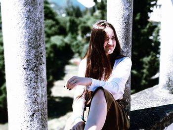 Young woman standing on tree trunk