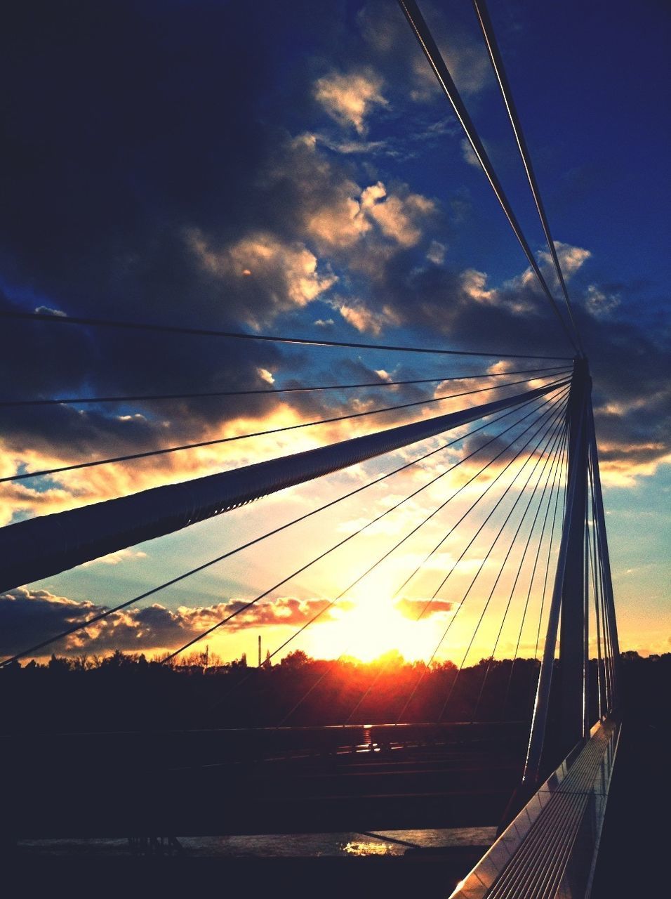 sunset, sky, connection, sun, transportation, sunlight, cloud - sky, cable, low angle view, cloud, orange color, sunbeam, power line, silhouette, built structure, bridge - man made structure, electricity pylon, outdoors, no people, lens flare