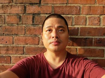 Portrait of young man against brick wall