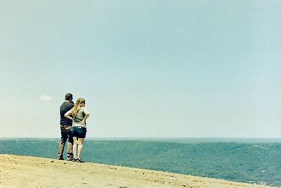 Full length of friends at beach against sky