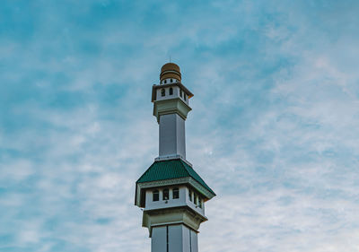 Low angle view of lighthouse by building against sky