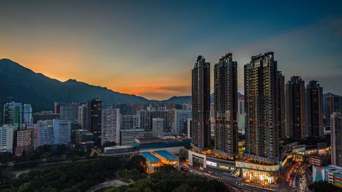 Illuminated buildings in city against sky during sunset