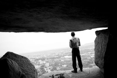 Rear view of man standing by cave