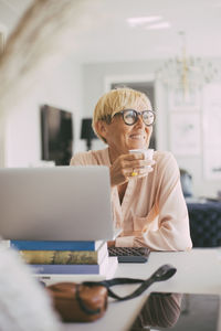 Woman having coffee at table working from home