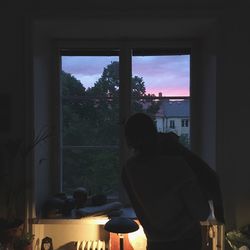 Rear view of man looking through window