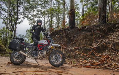 Woman posing on her scrambler type motorbike in thai forrest