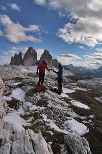 Rear view of man standing on snow covered mountain against sky. 3 cime di lavaredo, dolomiti, italy