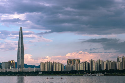 Buildings by river against sky in city