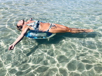 Full length of woman lying in swimming pool