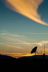 Silhouette of telephone pole against sky during sunset