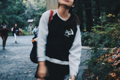 Midsection of woman standing against trees