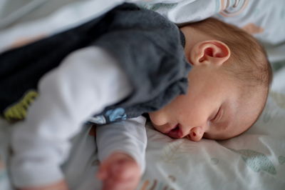 Close-up of cute baby boy lying on bed at home