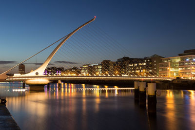 Illuminated samuel beckett bridge over river against sky