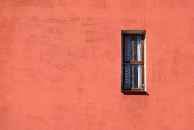 Window on the red facade of the house in the city