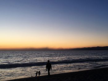 Silhouette people on beach against sky during sunset