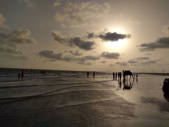 People on beach against sky during sunset