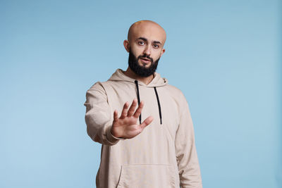 Portrait of young man standing against blue background