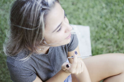 Woman smoking marijuana joint on field