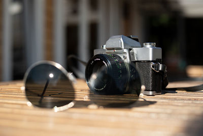 Camera and sunglasses on table in the sun
