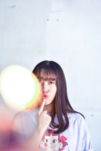 Portrait of beautiful young woman gesturing while standing against wall