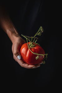 Cropped hand of woman holding heart shape against black background