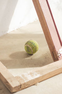 A tennis ball under the shade of a window pane. 