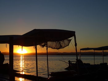 Silhouette boats in sea against sky during sunset