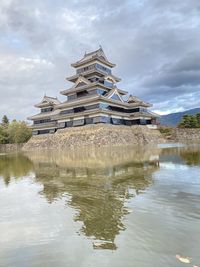 Traditional building by lake against sky