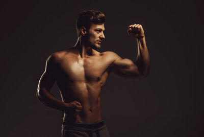 Full length of shirtless man against black background