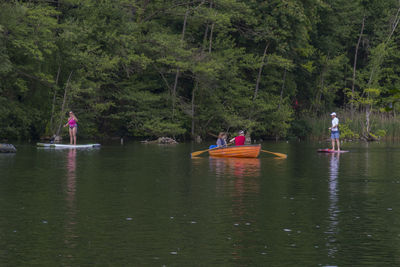 People on boat in river against trees in forest