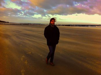 Full length of man standing on land against sky during sunset