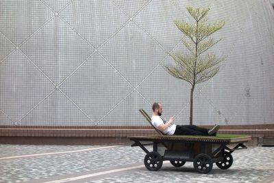 Woman sitting on wall in city
