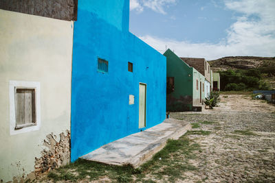 Alley amidst buildings against blue sky