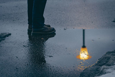 Low section of person standing on wet street