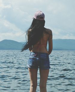 Young woman standing in sea against sky