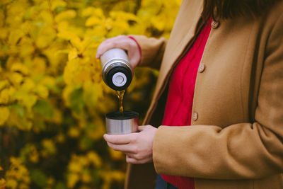 Midsection of woman pouring drink in bottle cap