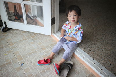 Portrait of young boy sitting in doorway