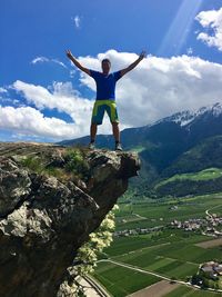 Full length of man with arms raised against sky