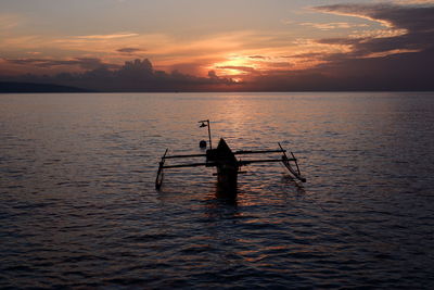 Silhouette person in sea against sky during sunset