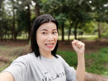 Portrait of woman clenching fist against trees