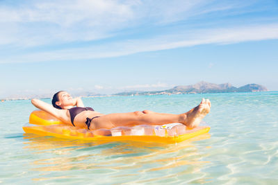 Young woman in sea against sky