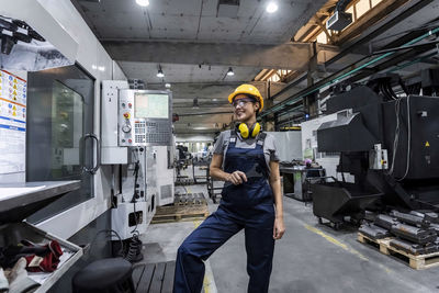 Smiling maintenance engineer standing by cnc machine in modern factory