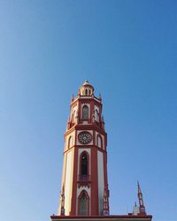 Low angle view of clock tower against clear blue sky