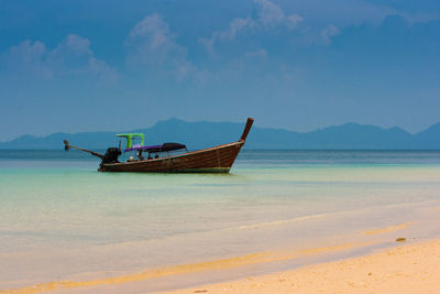 Fishing boat on beach against sky