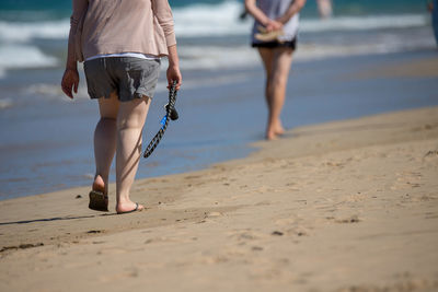 Low section of women walking at beach